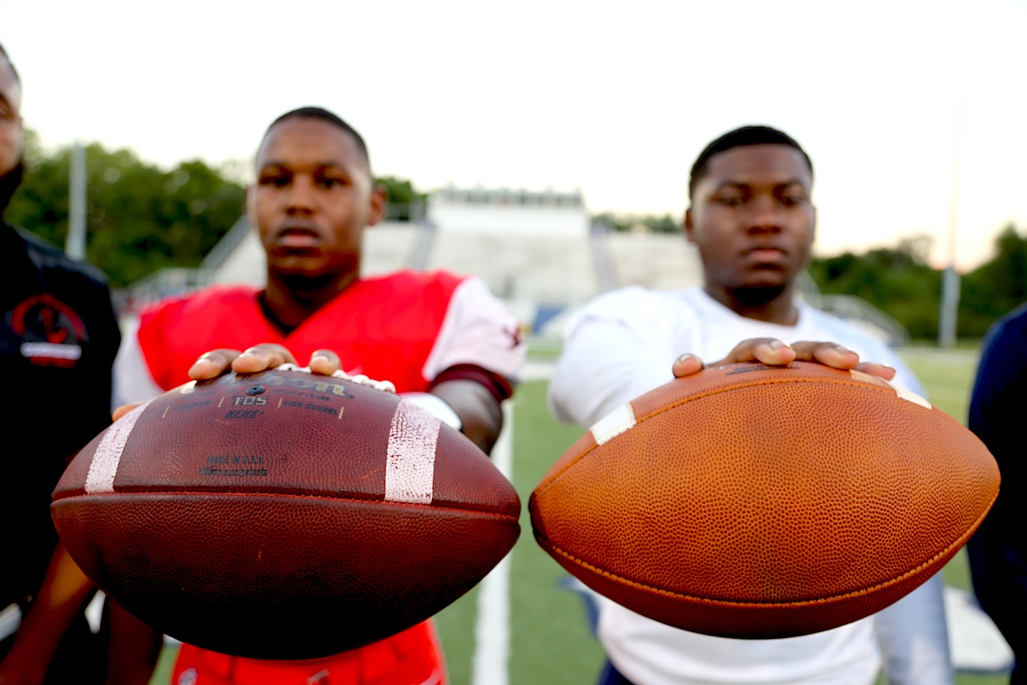 Two football players holding up footballs
